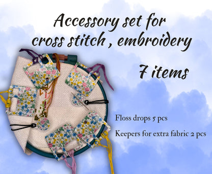 Cross stitch accessory set with floss drops and keepers on a blue background